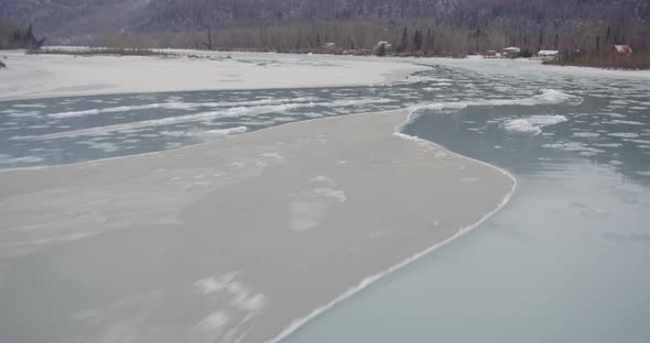Aerial helicopter shot track across snowy, rocky Alaskan mountain ridge, drone footage