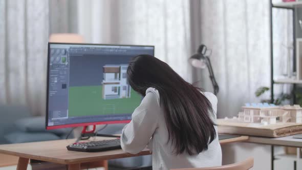 Asian Woman Engineer Stretching While Designing House On A Desktop At Home
