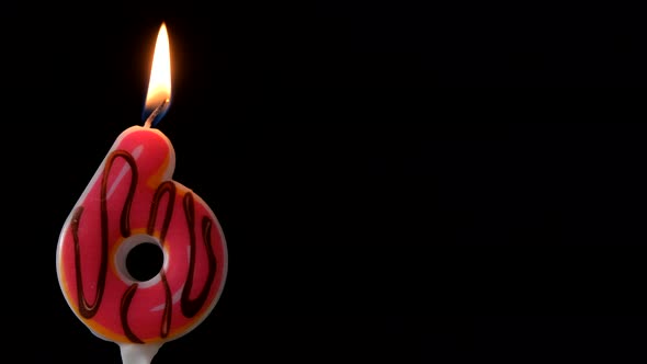 Number 6 Birthday Celebration Donut Candle Against a Black Background