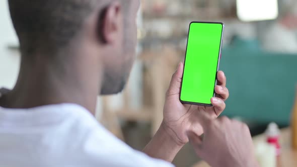 Young African Man Using Smartphone with Green Chroma Screen