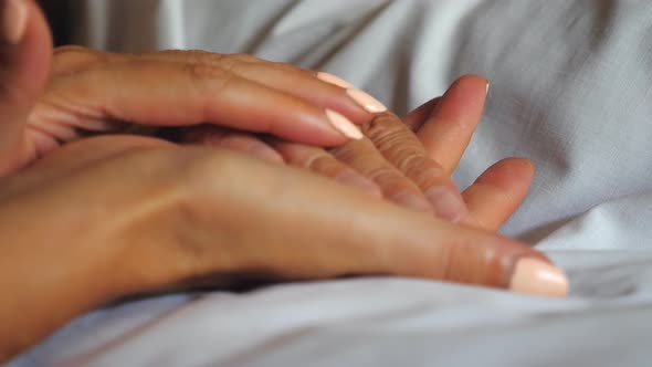 Unrecognizable Woman Holding Hand of Her Old Mother Lying in Bed Showing Care or Love. Daughter