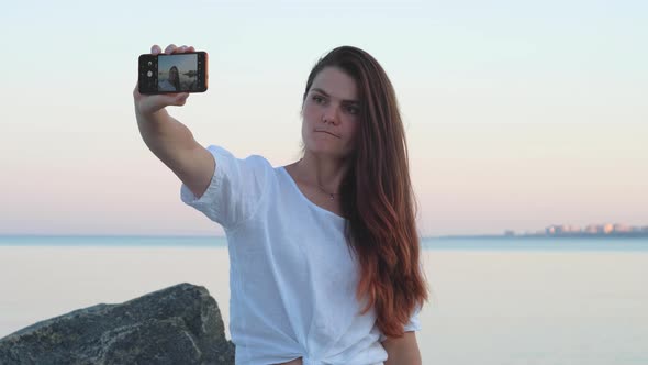 Young Woman Takes A Selfie By The Sea In The Evening