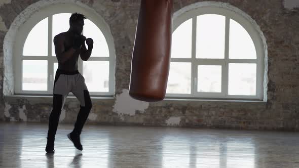 Shirtless Male Boxer Enjoying Training at Boxing Studio with Wrapped Hands