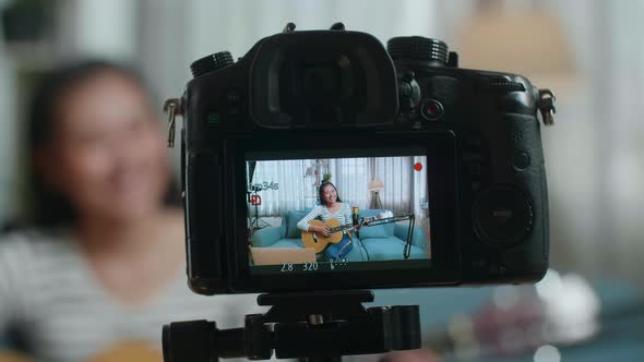 Close Up Of A Camera Monitor Recording Asian Woman Holding A Guitar And Smiling While Live Stream