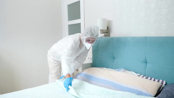 Hotel Maid in Protective Medical Suit and Gloves Tidying Hotel Room