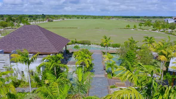 Aerial flyover Equestrian Center Stables at Cap Cana with large green grass field in Dominican Repub