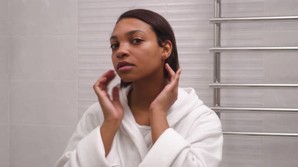 The Woman in the Bathroom Straightens Her Hair and Looks at Her Face