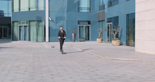 Confident Businessman in Suit Riding on Electric Scooter Outdoor