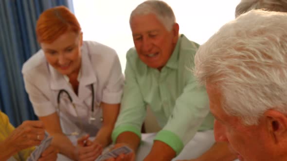 Doctor watching senior people playing cards