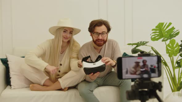 Cheerful European Influencers Creating a New Video While Sitting on a White Couch in Their Modern