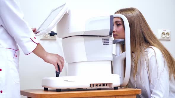Woman checking eye in clinic. Optometrist checking vision of young beautiful woman
