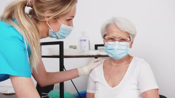 Senior Lady with Grey Hair and Her Glasses on Smiling Sincerely at the Doctor While Wearing a Face