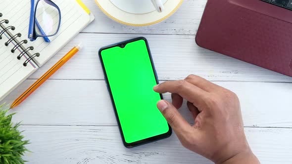 Flat Composition of Man's Hand Browsing Smart Phone on Office Desk