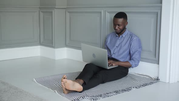 a Young AfricanAmerican Student Works on a Laptop at Home Sitting on the Floor