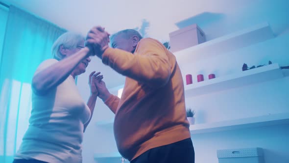 Happy Old Married Couple Dancing with Disco Lights in Hotel Room