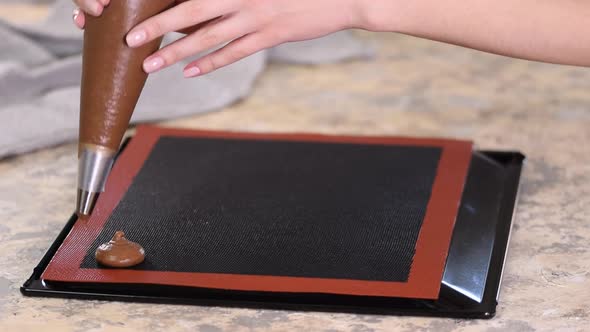 Cooking Chocolate Profiteroles, Female Hands Squeeze the Dough From the Bag Onto Baking Sheet