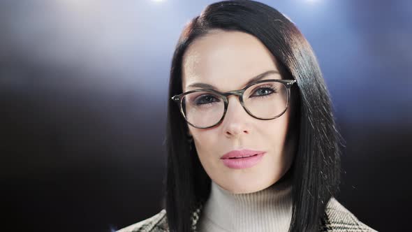 Middle Age Woman with Glasses Close Up Portrait on Dark Background. Casual Business Woman Looking