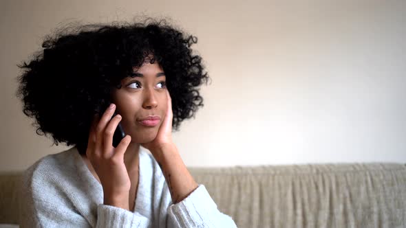 Young lack woman speaking on smartphone at home