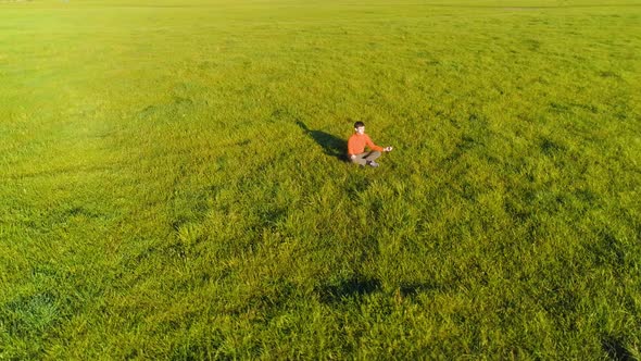 Low Altitude Radial Flight Over Sport Yoga Man at Perfect Green Grass. Sunset in Mountain.