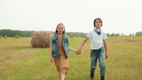 Teenager Couple Walking on Rural Field on Haystack Background