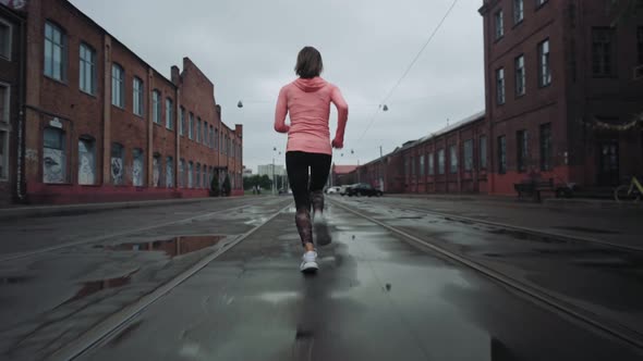 Young Woman Running Along an Old City District Street