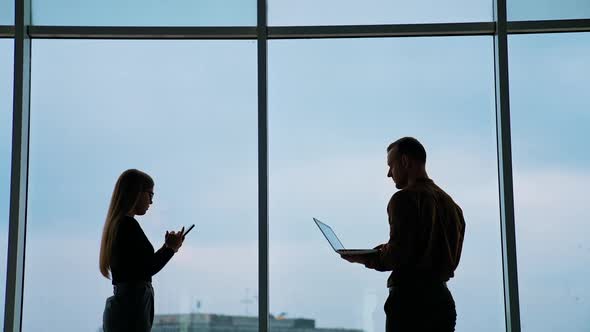 Two coworkers use laptop and smartphone. Teamwork, coworking concepts.