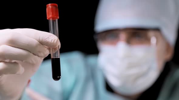 Close Up Medical Doctor Performs a Blood Test. The Technician Holds a Tube with a Blood Test in His