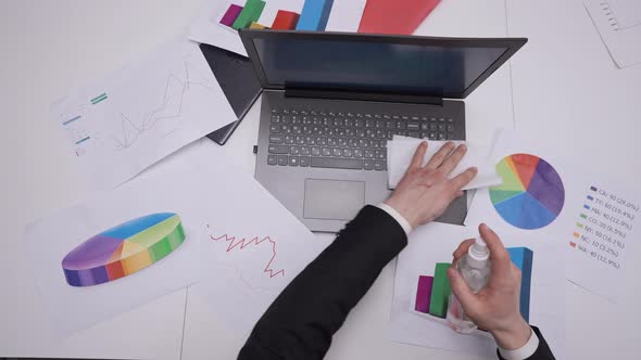 Top View Male Hand Disinfecting Laptop with Sanitizer in Slow Motion