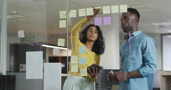 Video of happy diverse businesswoman and businessman brainstorming in office