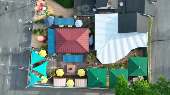 Top down aerial of outdoor restaurant, tiki bar. Colorful canopies and rooftop. America urban settin