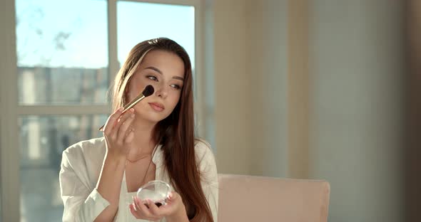 Beautiful Girl Doing Makeup with a Brush in Studio