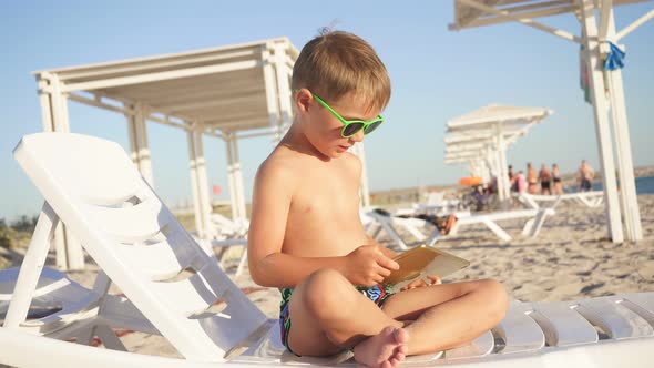 Funny Child Using a Tablet on the Beach.