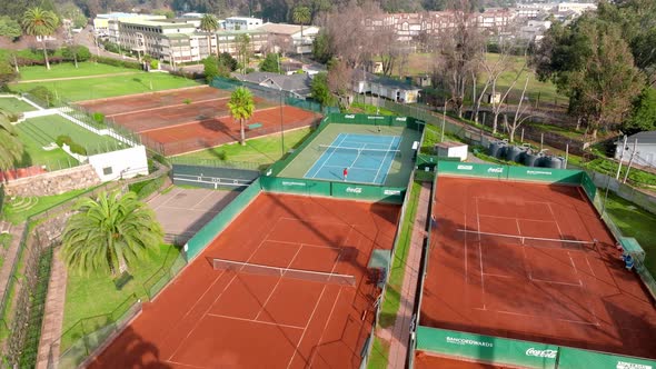 Drone flying to two people playing tennis in leisure outdoors center of South America