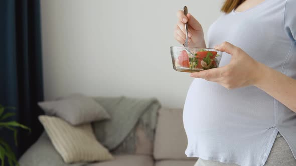 Pregnant Woman in Home Clothes Holding a Salad of Fresh Vegetables and a Fork