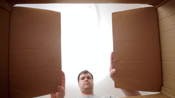 POV of Young Man Opens Cardboard Box and Gets Amazed