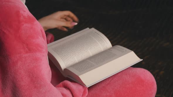 Young Woman in Pink Pajamas Sitting Reads a Book