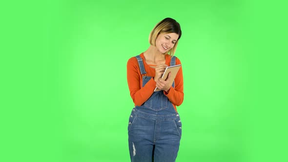 Girl Stands and Thinks, Then Happy Writes with Pencil in Notebook. Green Screen