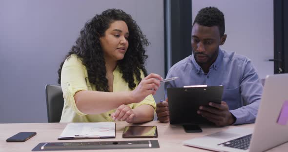 Happy diverse couple of business people working together in modern office