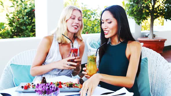 Friends having mocktail while taking selfie on mobile phone