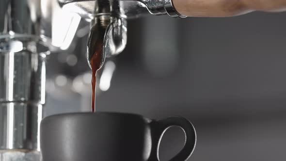 Slow Motion Espresso Pour From Single Spout Portafilter Into Black Cup
