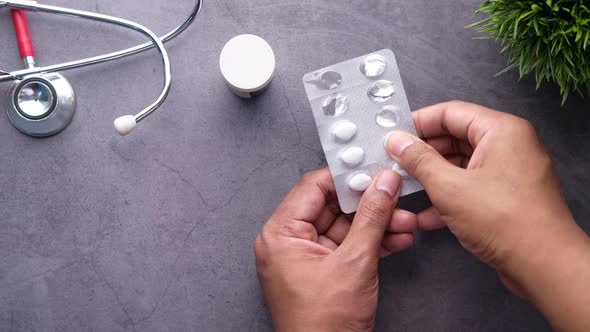  Man Hand Taking Pills From Blister Pack on Black Background 