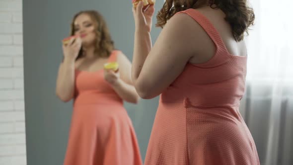 Happy and Satisfied With Oversize Body Girl Eating Donuts in Front of Mirror