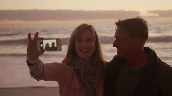 Active senior couple taking selfie on beach
