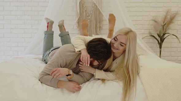 Young Entrepreneur and His Beautiful Businesswoman Girlfriend Laying Down on Their Bed Playing with