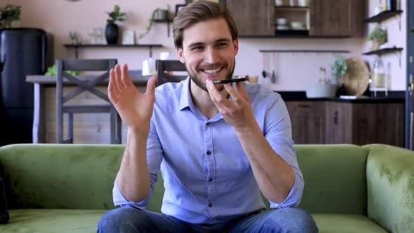 Confident business man holding smartphone near mouth for recording voice message