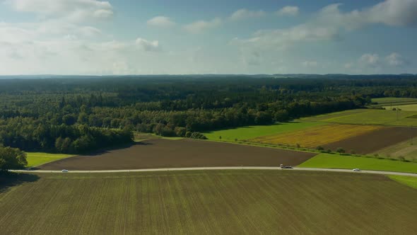 Rural countryside at a beautiful day at the end of the summer as aerial pullback shot with a road an