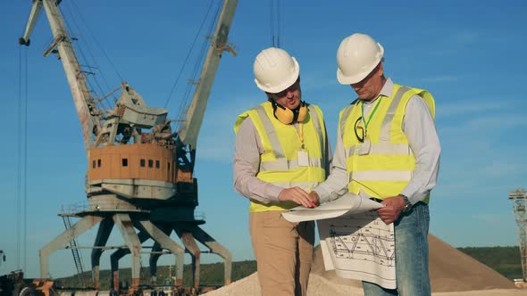 Two Engineers Are Talking Next To Loading Cranes