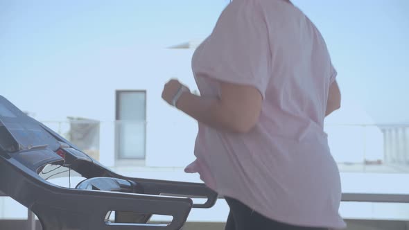 Big woman running on a treadmill on the top of a building