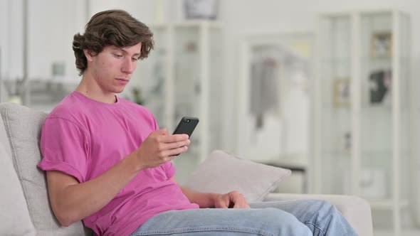 Attractive Young Casual Man Using Smartphone at Home