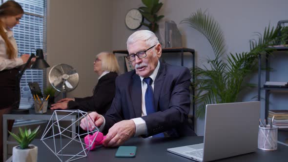 Business Man Making Fitness Dumbbells Exercises After Hard Work While Sits at Office Desk Workplace